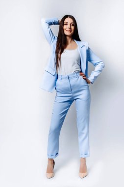 Düz saçlı, mavi takım elbiseli, yüksek topuklu bej ayakkabılı Hintli bir iş kadını. Gülümsüyor. Beyaz arkaplanda tam vücut uzunluğu izole edildi