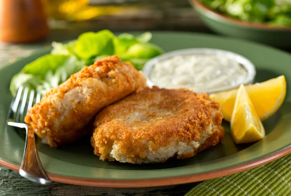 A plate of delicious homemade fishcakes with lemons, green salad and tartar sauce. — Stock Photo, Image