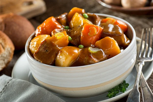 Een heerlijke kom van rijke en hartige rundvlees stoofpot met aardappel, biet, wortel, selderij en erwten. — Stockfoto