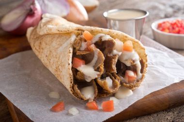 A delicious, authentic east coast take out donair with tomato, onion and sauce. clipart
