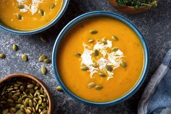 Delicious creamy homemade pumpkin soup with cream and pumpkin seed garnish. — Stock Photo, Image