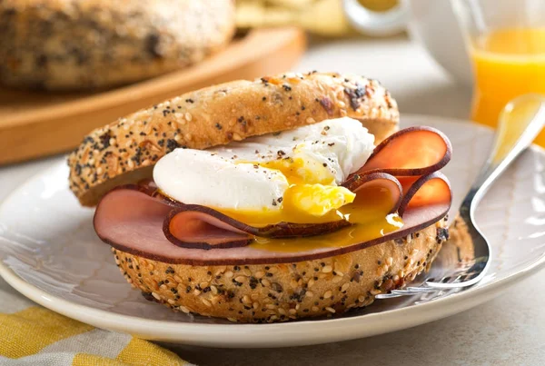 A delicious breakfast bagel with poached egg and black forest ham. — Stock Photo, Image