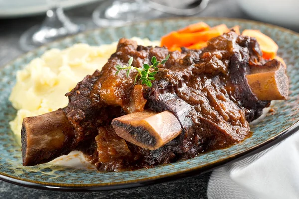 Heerlijke gestoofd rundvlees ribben met aardappelpuree en worteltjes. — Stockfoto