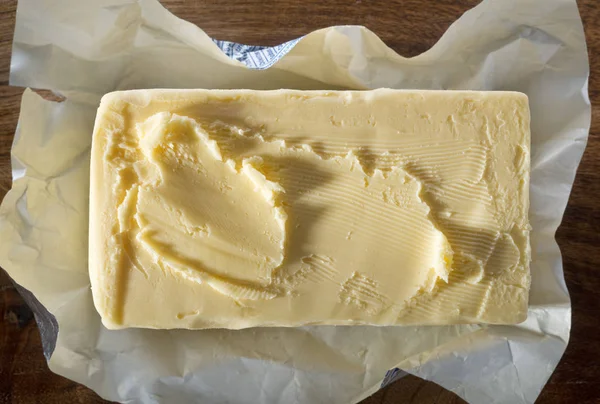 Bovenaanzicht van een geschraapt Messenblok boter op folie wrapper. — Stockfoto