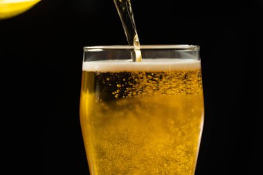 Siyah zemin üzerine bira dökülen kadehlerin yakın çekimi