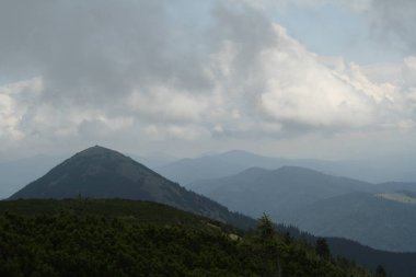 Ukrayna 'daki dağ manzarası, soldaki tepe Khomyak, ağaçlar, taşlar, yüksek bulutlar.
