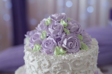 Wedding cake with flowers of cream - white and lilac shades clipart