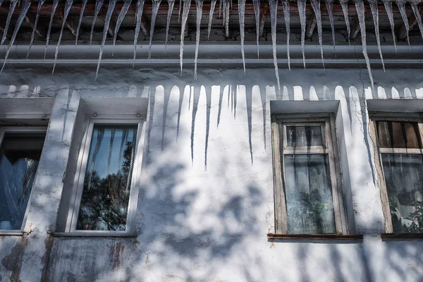 建筑物的屋顶上挂着长长的冰柱 挡住了窗户 — 图库照片