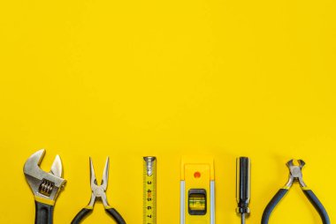 Sarı arkaplanda usta inşaatçı ve aksesuarlar için araçlar