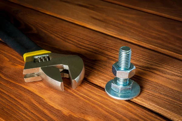 Chiave regolabile con dado e bullone in metallo su sfondo marrone vintage in legno — Foto Stock