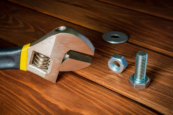 Chiave regolabile con dado e bullone in metallo su fondo vintage in legno — Foto Stock