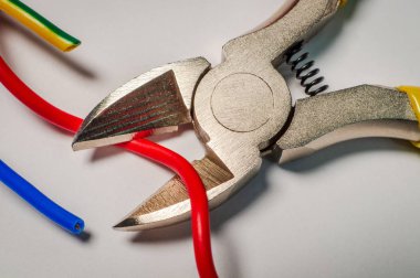 Gri bir arkaplanda elektrik kablosunu kesen pense aracı