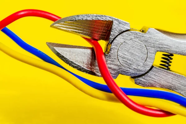 Sarı arka planda elektrik kablosunu kesen pense aracı