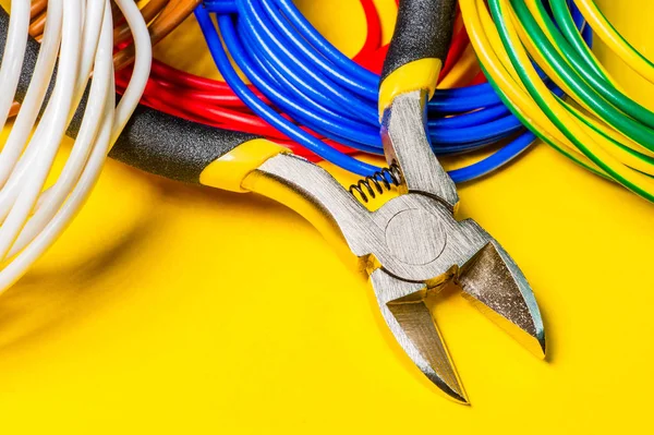 Alicates herramienta y cables para electricista primer plano sobre fondo amarillo — Foto de Stock