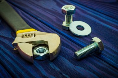 Üzerinde metal fındık ve cıvata bulunan ayarlanabilir anahtarlar mavi eski ahşap arka planda