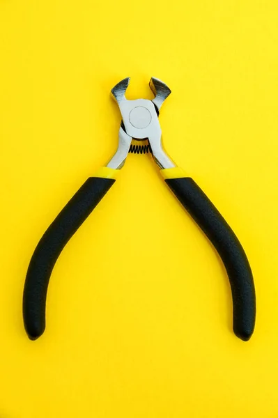 Single pliers tool with rubber handles for the master electrician on yellow background — Stock Photo, Image