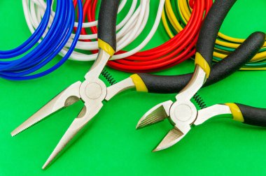 Elektrikçi için pense aracı ve kablolar yeşil arkaplanda yakın plan