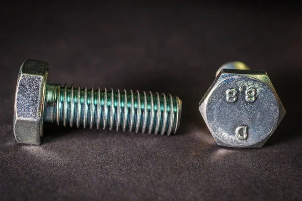 Two metal bolts on black background are used in construction Stock Photo