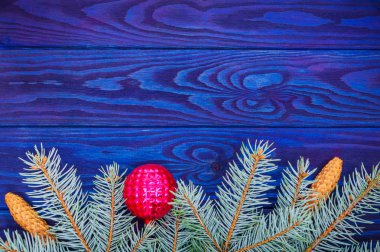 Mavi ahşap bir arka planda ladin ve oyuncaklardan oluşan güzel bir Noel sınırı