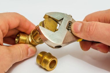 İşçi tesisat tesisatlarını bağlar ve ayarlanabilir ingiliz anahtarıyla onarım yapar