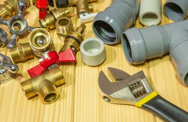 Ahşap bir arka planda tesisat tamiri için yedek parça ve aksesuarlar.