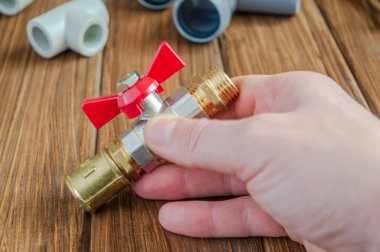 Usta, tesisatların vidalandığı kırmızı hijyenik musluğu tutuyor.