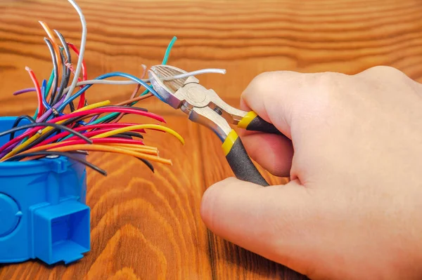 Mestre eletricista corta um fio na caixa de junção — Fotografia de Stock