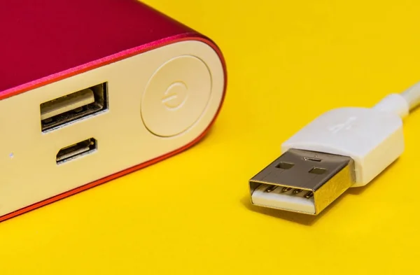 USB charger cable and power bank on yellow surface close up