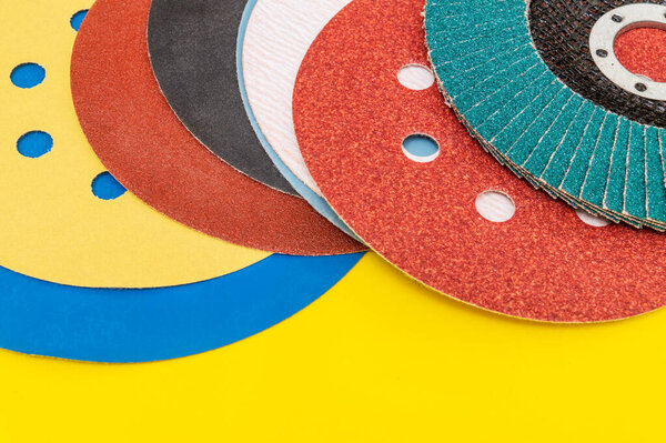 Set of abrasive tools and sandpaper on yellow background