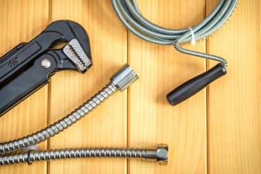 Set of tools and hose for master plumber on wooden boards