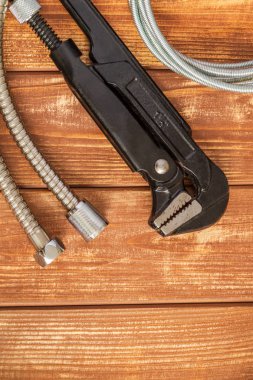 Necessary set of tools and hose for master plumber on old wooden boards