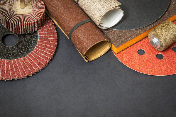 Big set of abrasive tools and multicolored sandpaper on black background