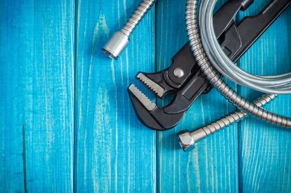 Necessary set of tools and hose for plumbers on blue vintage wooden boards — Stock Photo, Image