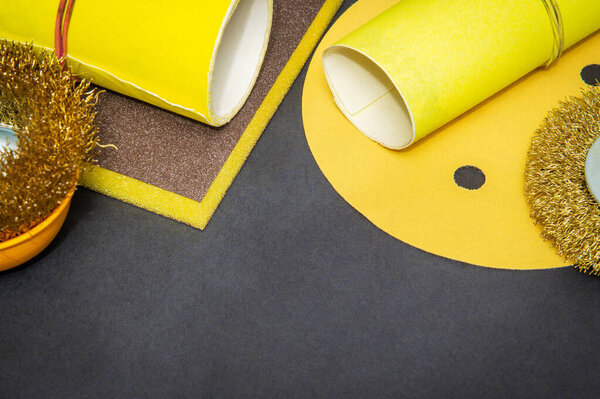 Big set of abrasive tools and yellow sandpaper on black background