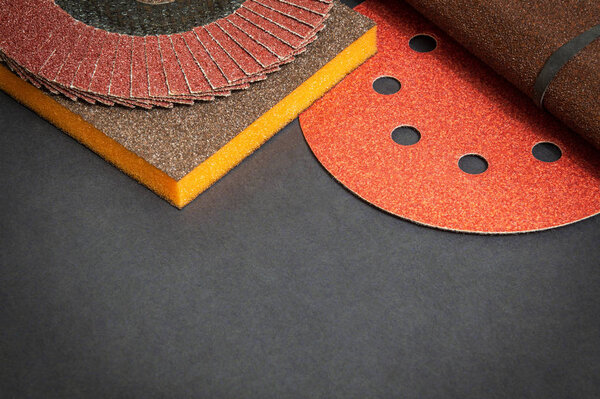 Big set of abrasive tools and multicolored sandpaper on black background