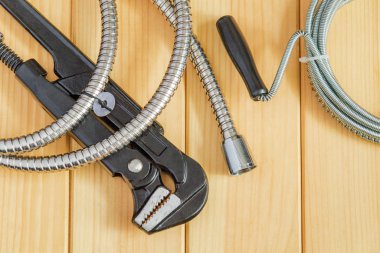 Ahşap tahtalardaki tesisatçılar için gerekli alet ve hortumlar.