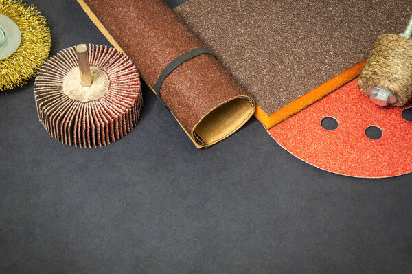 Big set of abrasive tools and multicolored sandpaper on black background
