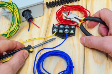 Üstat bağlanmak için bir elektrikli alet ve kablolar tutuyor