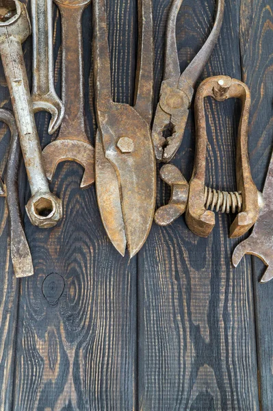 Old tools stacked after work on black vintage wood background