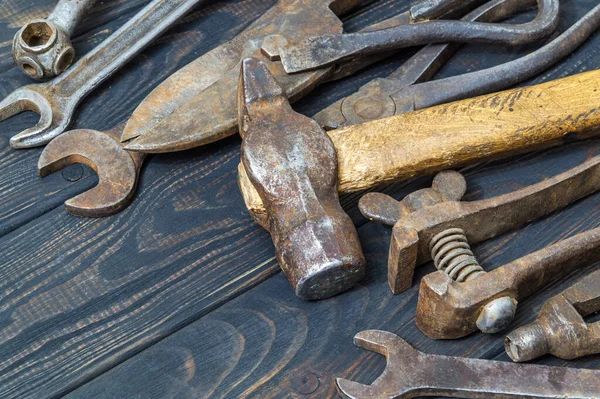 Old tools stacked after work on black vintage wood background — Stock Photo, Image