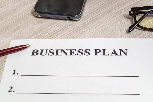 Forma y pluma en blanco para la elaboración de un plan de negocio sobre la mesa — Foto de Stock