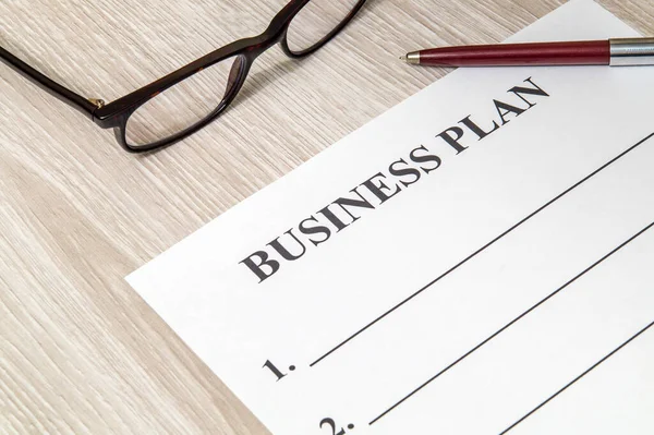 Forma y pluma en blanco para la elaboración de un plan de negocio sobre la mesa — Foto de Stock