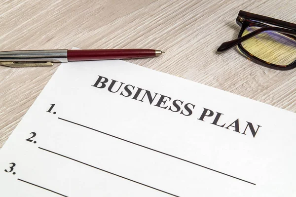 Forma y pluma en blanco para la elaboración de un plan de negocio sobre la mesa — Foto de Stock