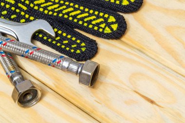 Tesisat ekipmanları tamir aletleri ayarlanabilir ingiliz anahtarı ve hortumu, eldivenler, ahşap tahtalarda esnek bağlantı