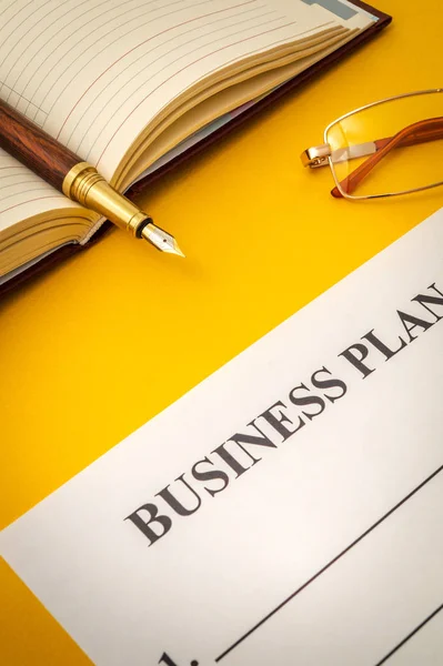 Forma en blanco y pluma para la elaboración de un plan de negocio sobre la mesa amarilla — Foto de Stock