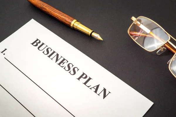 Forma en blanco y bolígrafo, gafas para elaborar un plan de negocios sobre mesa negra — Foto de Stock