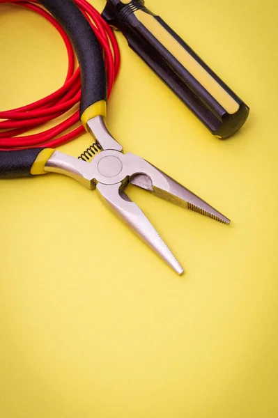 Herramientas eléctricas y alambre sobre fondo amarillo para la reparación de sistemas energizados o comunicaciones —  Fotos de Stock