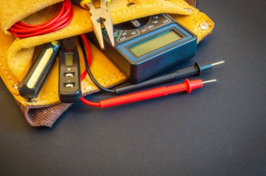 Profesyonel elektrikçi tarafından tamir ya da inşaat öncesi hazırlanmış siyah arka planda süet çantadaki büyük aletler.
