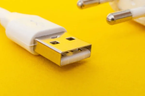 New USB charger cable on yellow surface close up often used for charging a smartphone or tablet