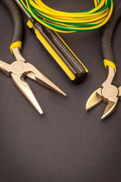 Electrician's tools and wire on a black background for repairing energized systems or communications